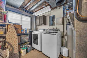 Washroom featuring carpet flooring, electric panel, washer and clothes dryer, and cabinets