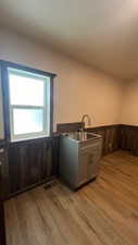 Kitchen featuring light hardwood / wood-style floors, sink, and wooden walls