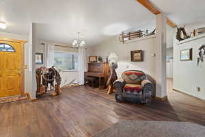 Entrance foyer with an inviting chandelier, dark hardwood / wood-style floors, and vaulted ceiling