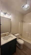 Full bathroom with shower / tub combination, toilet, vanity, and hardwood / wood-style flooring