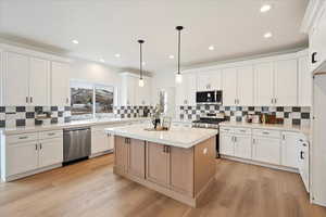 Kitchen with white cabinetry, pendant lighting, and appliances with stainless steel finishes.