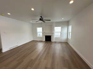 Family room featuring laminate flooring and ceiling fan. Gas fireplace with mantle and window set.