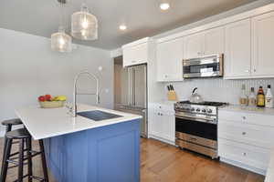 VIRTUALLY STAGED - Kitchen featuring sink, decorative light fixtures, high end appliances, and an island with sink