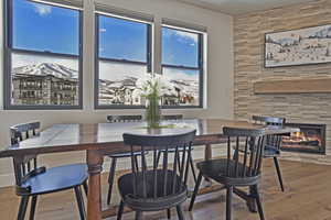 VIRTUALLY STAGED - Dining room with a stone fireplace and wood-type flooring