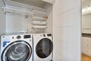 Laundry room featuring light wood-type flooring and washing machine and clothes dryer