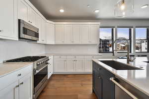 Kitchen with white cabinets, decorative light fixtures, and stainless steel appliances