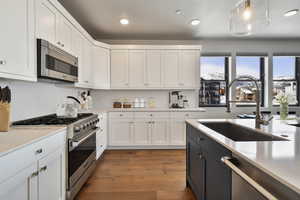 VIRTUALLY STAGED - Kitchen with white cabinets, stainless steel appliances, and hanging light fixtures