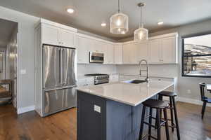 Kitchen featuring white cabinetry, high quality appliances, sink, and light stone countertops