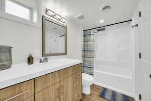 Full basement bathroom with hardwood / wood-style flooring, vanity, toilet, and shower / bath combo