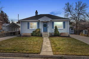 Bungalow-style home featuring a front lawn and a carport