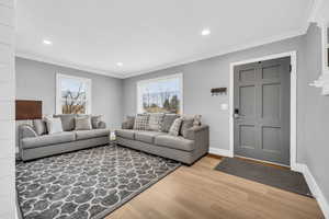 Living room with hardwood / wood-style floors, a wealth of natural light, and ornamental molding