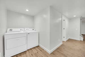 Laundry room with light hardwood / wood-style floors and independent washer and dryer