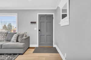 Entrance foyer featuring light hardwood / wood-style floors and crown molding