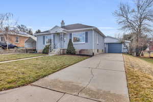 Bungalow-style home with a carport, a garage, an outbuilding, and a front yard