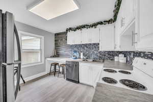 Kitchen featuring sink, white cabinets, stainless steel appliances, and light hardwood / wood-style floors