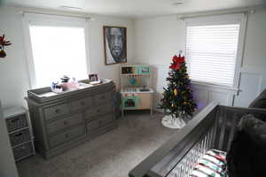 Carpeted bedroom featuring a crib