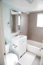 Full bathroom featuring hardwood / wood-style floors, vanity, tiled shower / bath combo, and toilet