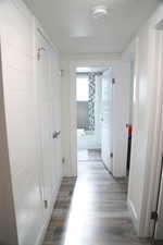 Hallway with a textured ceiling and light wood-type flooring