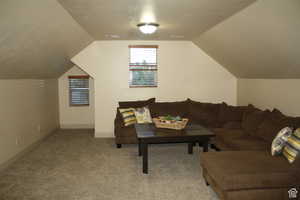 Living room featuring a textured ceiling, light carpet, and lofted ceiling