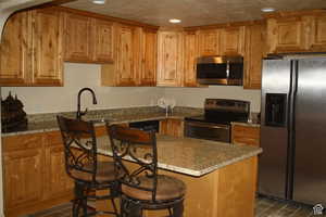 2nd Kitchen with light stone countertops, a kitchen bar, stainless steel appliances, and sink