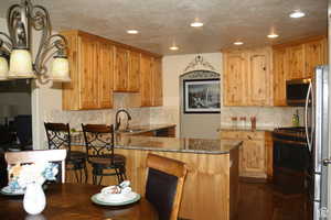 Kitchen with a breakfast bar, dark wood-type flooring, sink, light stone countertops, and appliances with stainless steel finishes