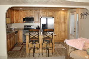 2nd Kitchen with stone counters, a center island, sink, stainless steel appliances, and a breakfast bar area