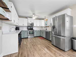 Kitchen with white cabinets, ceiling fan, sink, and appliances with stainless steel finishes