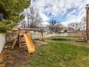 View of playground with a trampoline and a yard