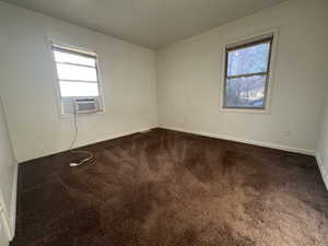 Spare room featuring dark colored carpet and cooling unit