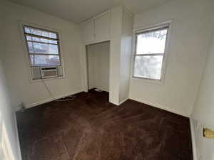 Unfurnished bedroom featuring a closet, cooling unit, and dark colored carpet