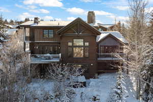 Snow covered back of property featuring a balcony