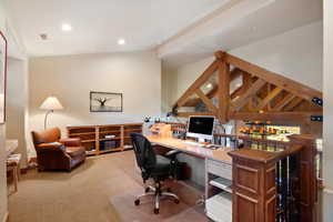 Carpeted office space featuring lofted ceiling