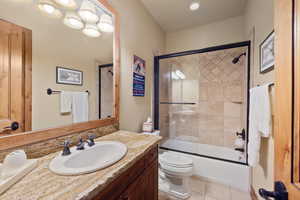 Full bathroom with tile patterned flooring, vanity, toilet, and enclosed tub / shower combo