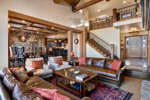 Living room with carpet, beam ceiling, a notable chandelier, and a high ceiling