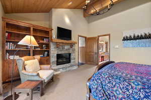 Carpeted bedroom featuring wooden ceiling, a fireplace, and high vaulted ceiling