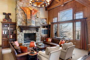 Living room with wood walls, light carpet, high vaulted ceiling, a fireplace, and a chandelier