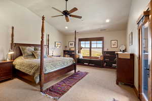 Carpeted bedroom with ceiling fan and lofted ceiling