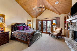 Bedroom with wooden ceiling, french doors, access to exterior, a fireplace, and light colored carpet