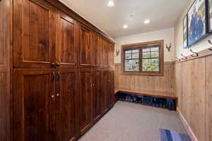 Mudroom featuring light carpet and wooden walls