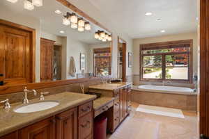 Bathroom with tile patterned floors, vanity, and tiled bath