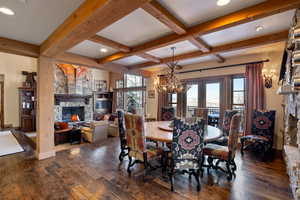 Dining space with coffered ceiling, dark hardwood / wood-style floors, a fireplace, and an inviting chandelier