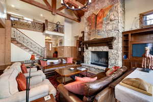 Living room featuring beam ceiling, a fireplace, and high vaulted ceiling