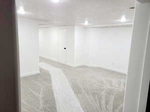 Empty room featuring a textured ceiling and light carpet