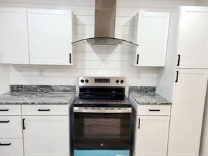 Kitchen with white cabinets, island range hood, stainless steel electric range oven, and stone countertops