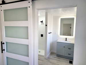 Bathroom with hardwood / wood-style floors, vanity, walk in shower, and a textured ceiling