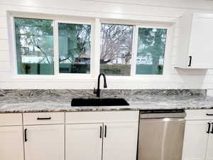 Kitchen with dishwasher, white cabinets, and sink