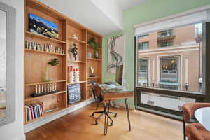 Office with built in shelves and light wood-type flooring