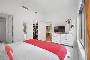 Bedroom with a spacious closet, a closet, and light carpet