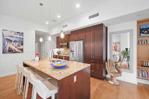 Kitchen with light stone countertops, sink, pendant lighting, and appliances with stainless steel finishes