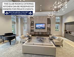 Living room with wood-type flooring, a notable chandelier, and a high ceiling